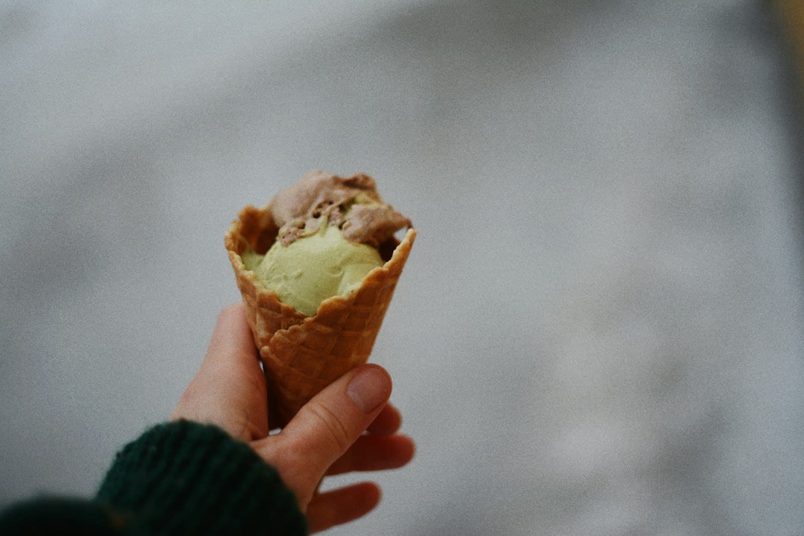 Hand som håller en strut med pistage- och chokladgelato